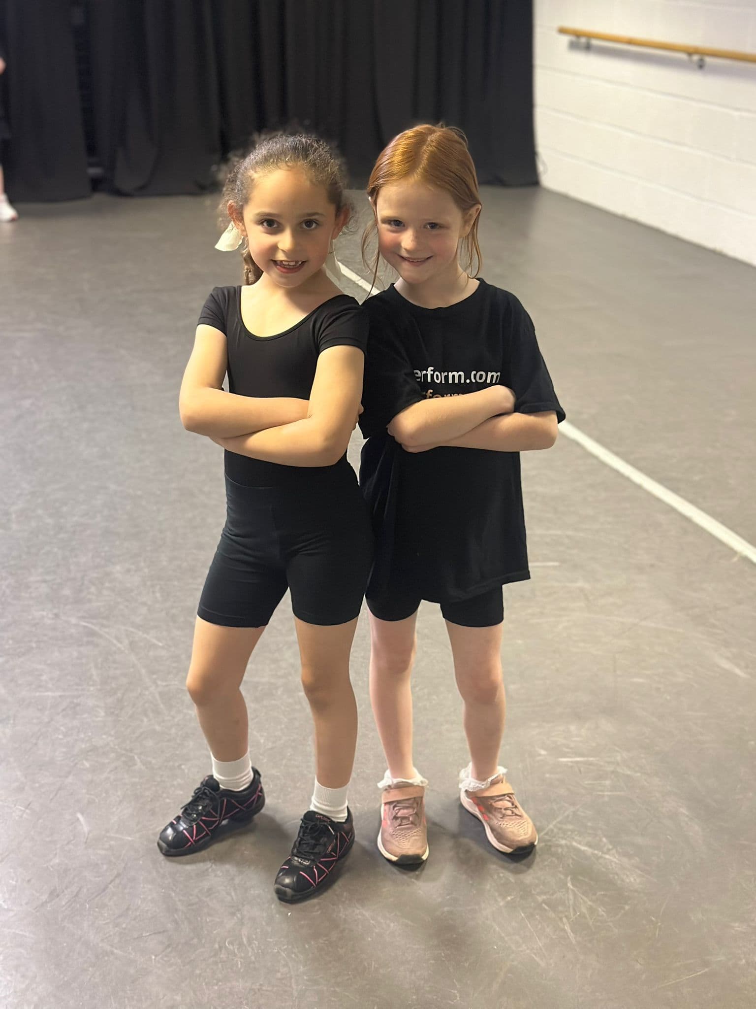 Two junior dancers smiling together before class
